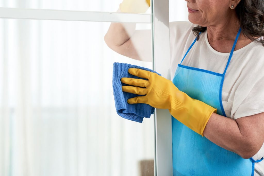 cropped woman cleaning window wearing special apron
