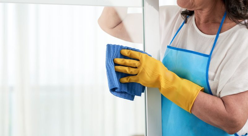 cropped woman cleaning window wearing special apron